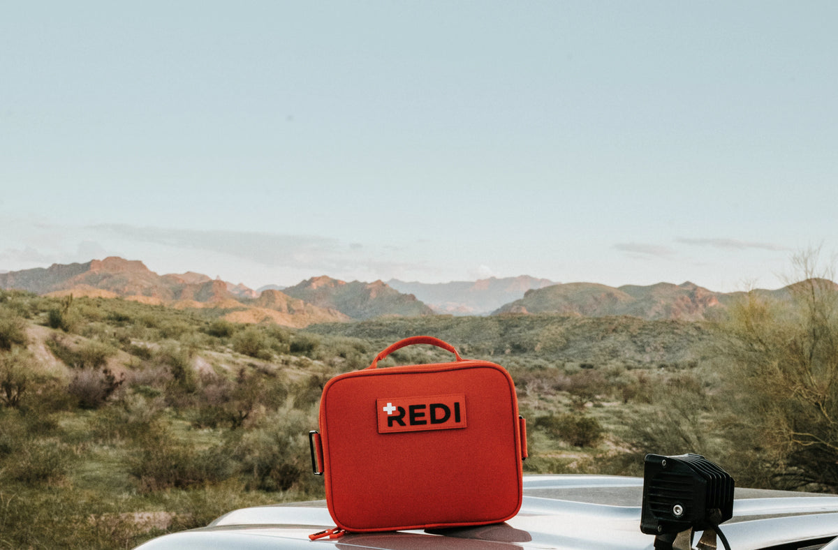 REDI Roadie readiness kit, an orange car emergency kit, sitting on a vehicle roof in the desert