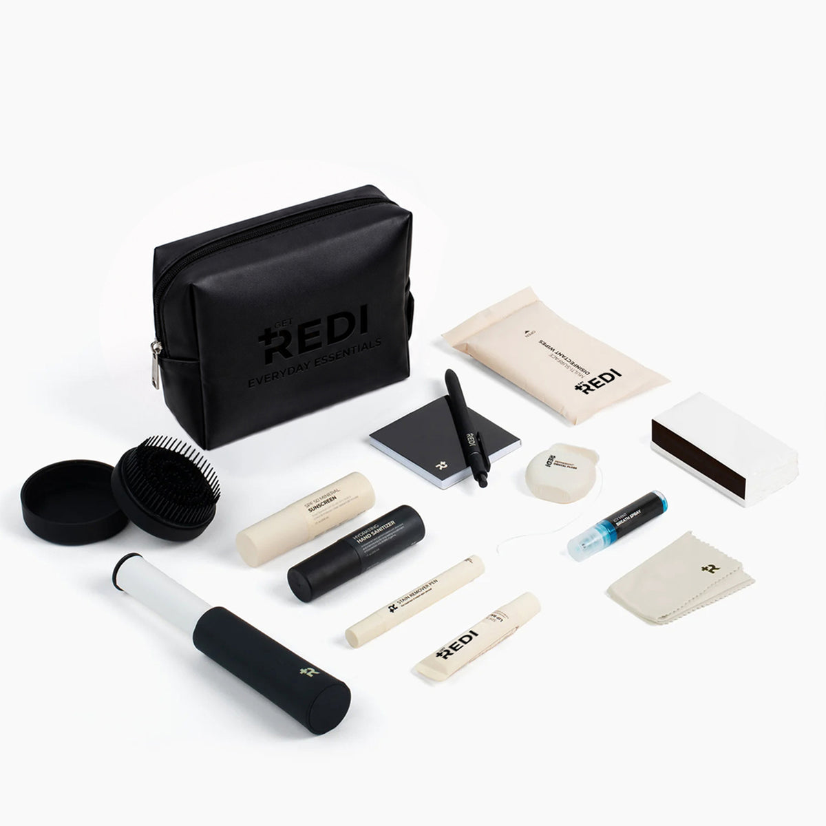 Everyday Essentials Bag with its 13 travel essentials laid out: sunscreen, hand sanitizer, lip balm, hair brush, stain pen and more